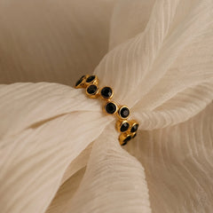 Gold bracelet with black stones on a beige fabric background