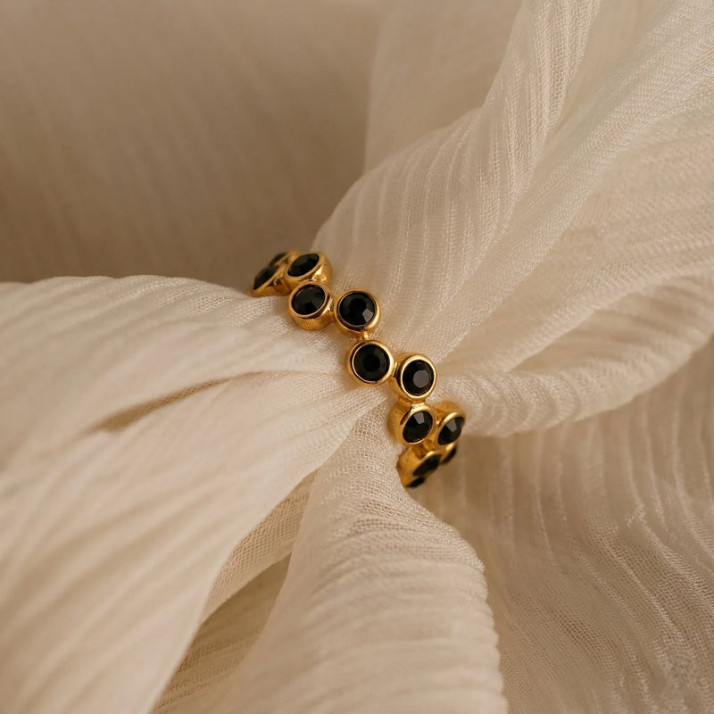 Gold bracelet with black stones on a beige fabric background