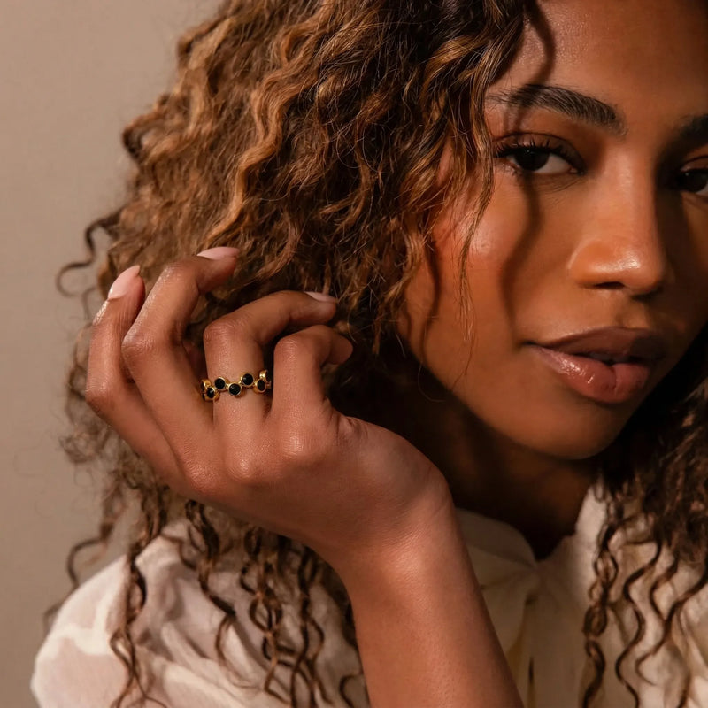 Woman with curly hair wearing a gold ring, close-up portrait.